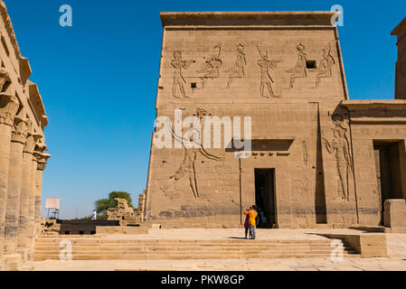 Due donne turisti tenendo selfie con selfie stick al pilone esterno e il Tempio di Philae, Fiume Nilo, Aswan, Egitto, Africa Foto Stock