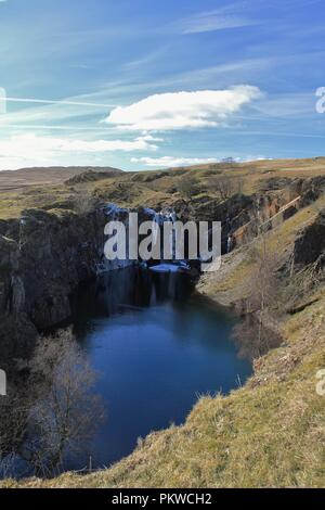 Regno Unito, Cumbria, Coniston. Vista verso la cascata ghiacciata dalla cava Banishead Torver comune nel Lake District inglese. Foto Stock