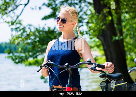 Sorridente giovane donna in piedi con la bicicletta Foto Stock