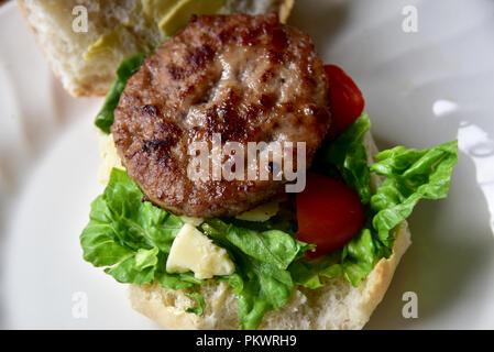 Home preparazione alimentare. In casa carni bovine chips burger e insalata preparati in una cucina privata. Immagine mostra insalata di lattuga, Formaggio, pomodoro e patatine. Foto Stock