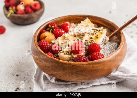 Farina di avena porridge con semi di Chia, bacche, burro di arachidi e semi di canapa in ciotola di legno. Vegano cibo sano concetto. Foto Stock