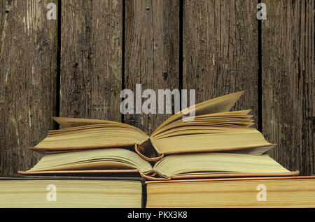 Pila di libri sullo sfondo di legno. molti libri pile. due libri aperti Foto Stock