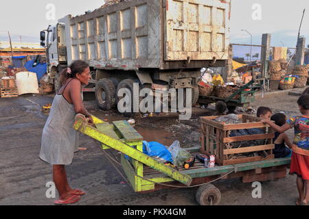 Cebu, Philippines-October 18, 2016: madre filippina prende i suoi figli a casa in un carrello dello scanner a superficie piana attraverso i detriti di un giorno lavorativo-mercato del carbonio-lo Foto Stock