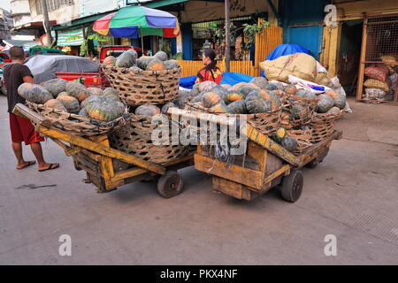 Cebu, Philippines-October 18, 2016: Portatori prendere una pausa mentre trasportano i cetrioli su un carrello. Mercato del carbonio più antico e il più grande mercato agricolo in città- Foto Stock