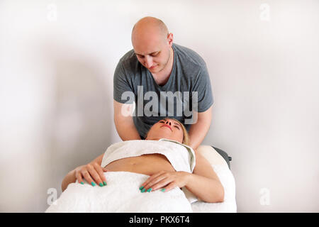 Massaggiatore massaggio collo femmina massaggio al lussuoso centro spa. Fisioterapista a ricevere e fare massaggio collo in massaggio relax studio. Foto Stock