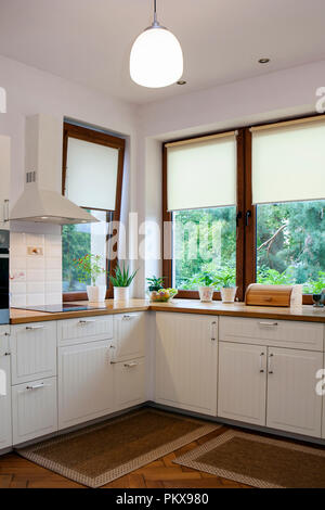 Cucina isola con bancone e sgabelli bar sotto il cofano in moderno  appartamento open space con pareti bianche con mobili e utensili Foto stock  - Alamy