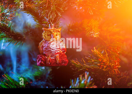 Lucido rosso decorazione palle di Natale owl con casa in colore viola-rosso fumo, su di un albero di Natale sfondo. Concetto di una moderna scheda di Natale. Foto Stock