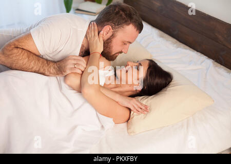 Un uomo si sveglia al mattino una donna teneramente baci Foto Stock