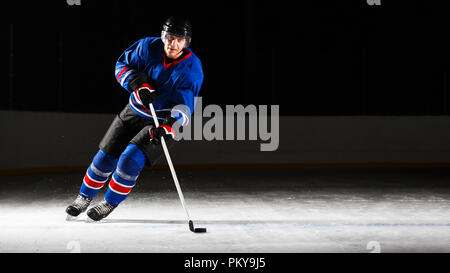 Giovane giocatore di hockey il pattinaggio su ghiaccio in attacco Foto Stock