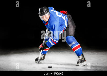 Giovane giocatore di hockey il pattinaggio su ghiaccio in attacco Foto Stock