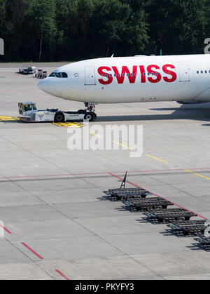 Un rimorchiatore di aeromobili è tirando un Airbus A340 della Swiss International Air Lines lontano dalla porta a Zurigo aeroporto internazionale. Foto Stock