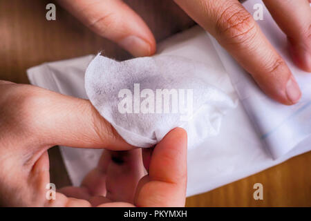 Donna mani tenendo fazzolettino umido dalla confezione. Close-up. Foto Stock