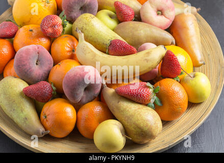 Coppa di frutta con Esotici frutti interi chiudere fino a rustico ciotola di legno Foto Stock