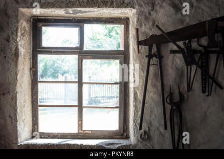 Finestra di età e strumenti di fabbro appeso su un vecchio muro, all'interno di una casa tedesca. Foto Stock