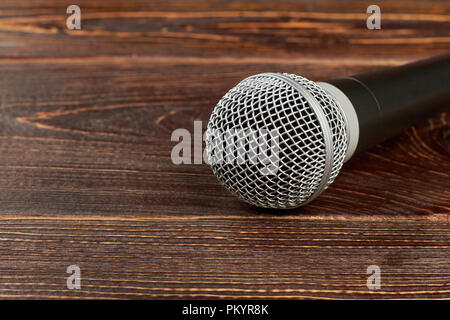 Microfono dinamico su sfondo di legno. Microfono grigio testurizzato sul tavolo di legno con copia spazio. Foto Stock