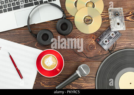 Equipaggiamento audio su sfondo di legno. Antiche e Moderne tecnologie multimediali, portatile incluso, cuffie, compact disc, cassette a nastro, microfono e vi Foto Stock