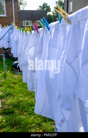 Camicie bianche appendere fuori ad asciugare su una linea di lavaggio in una zona residenziale giardino sul retro. Foto Stock