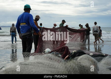 Di Banda Aceh e Aceh, Indonesia - 16 Settembre 2018: gruppo di pescatori tira manualmente i loro net fuori dall'oceano a Gampong Jawa Beach, Banda Aceh Foto Stock