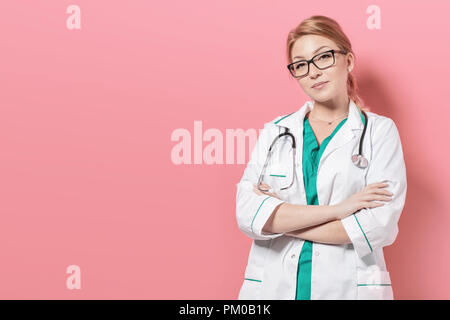 La donna in uniforme medico si erge su sfondo rosa. Foto con copyspace per il tuo spazio Foto Stock