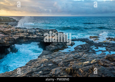 Un arco di roccia formata da una forma ripiegata tubo di lava in Kauai più a sud point Foto Stock