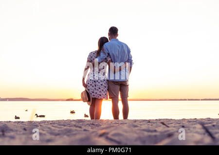 Paio di camminare sulla spiaggia al tramonto Foto Stock