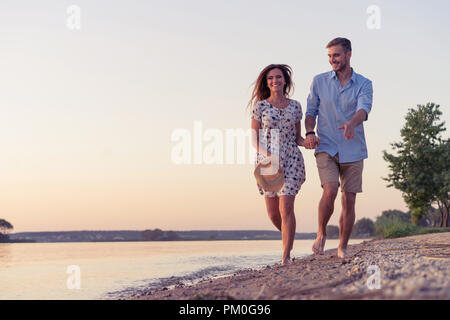 Paio di camminare sulla spiaggia al tramonto Foto Stock