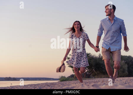 Paio di camminare sulla spiaggia al tramonto Foto Stock