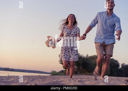 Paio di camminare sulla spiaggia al tramonto Foto Stock