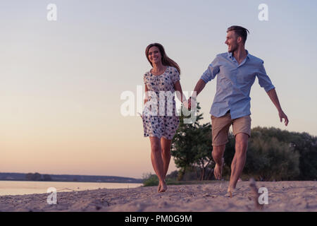 Paio di camminare sulla spiaggia al tramonto Foto Stock