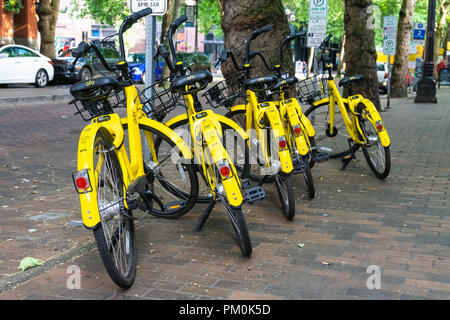 Gruppo di giallo condivisione Ofo moto parcheggiata su un marciapiede in Pioneer Square District nel centro cittadino di Seattle, Stati Uniti d'America. Ofo arrestare il suo funzionamento nel luglio 2018. Foto Stock