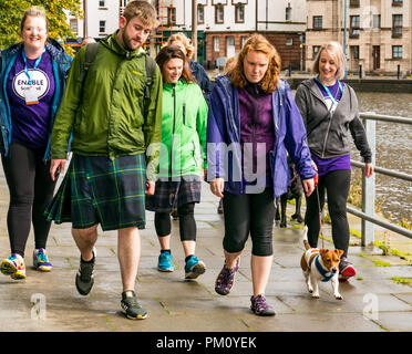 Leith, Edimburgo, Scozia, Regno Unito, 16 settembre 2018. Edinburgh Kilt Walk, sponsorizzato dalla Royal Bank of Scotland, si svolge oggi. I camminatori raccogliere fondi per un'associazione benefica di loro scelta. I kilt walkers raggiungono la Shore a Leith a circa 14 miglia. Un gruppo di escursionisti con un Jack Russell, un uomo che indossa un kilt e una donna che raccolta di denaro per la carità Enable Foto Stock