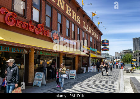 I minatori Imbarcadero 57 edificio con persone a piedi lungo la strada in Alaska boardwalk o waterfront, Seattle, nello stato di Washington, USA. Foto Stock