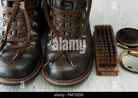 Close-up, dettaglio, Shoe Polish e spazzola per la pulizia di coppia di lavoro stivali marrone Foto Stock