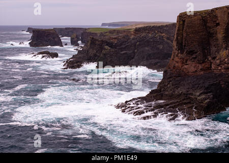 Il selvaggio Oceano Atlantico si blocca contro il mare di pile, rocce e scogliere lungo la costa occidentale delle Isole Shetland a Eshaness Foto Stock