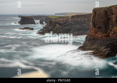 Il selvaggio Oceano Atlantico si blocca contro il mare di pile, rocce e scogliere lungo la costa occidentale delle Isole Shetland a Eshaness Foto Stock