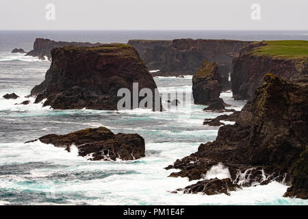 Il selvaggio Oceano Atlantico si blocca contro il mare di pile, rocce e scogliere lungo la costa occidentale delle Isole Shetland a Eshaness Foto Stock