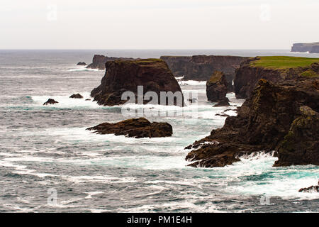 Il selvaggio Oceano Atlantico si blocca contro il mare di pile, rocce e scogliere lungo la costa occidentale delle Isole Shetland a Eshaness Foto Stock