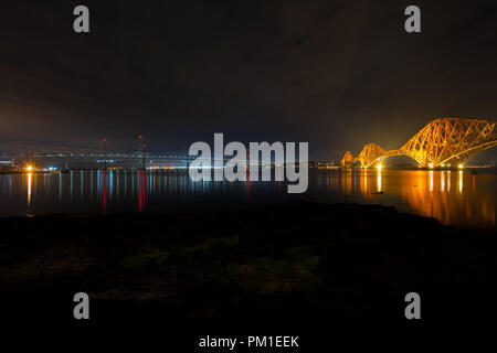 La storica rosso Vittoriano Forth Road Bridge rampa sulla destra con la nuova versione di Forth Road attraversamenti stradali sulla sinistra, presa a tarda notte con la bassa marea. Foto Stock