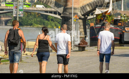 Quattro giovani a piedi lungo un sentiero lungo il fiume Vltava nel centro di Praga. Foto Stock