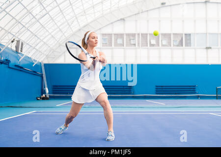 Giovane donna bionda giocando a tennis Foto Stock