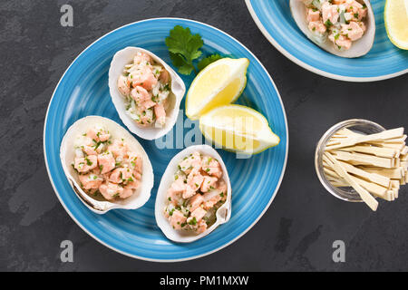 Freschi Fatti in casa salmone cileno ceviche con il succo di limone, la cipolla, l'aglio, il sale e il coriandolo, servita su conchiglie, fotografato overhead su ardesia Foto Stock