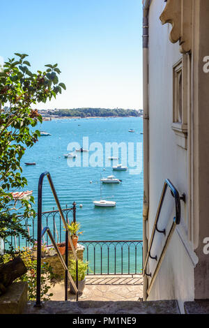 Le porte di una villa e un balcone giù per le scale e si affaccia sul fiume Rance in Dinard, Francia, con barche ormeggiate nel estuario nella distanza. Foto Stock