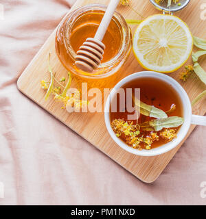 Tè con Linden, miele e limone. Il vassoio sul letto, il concetto di trattamento di raffreddori Foto Stock