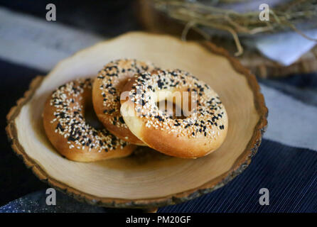 Fotografia di close-up bagel con semi di papavero su un supporto in legno Foto Stock