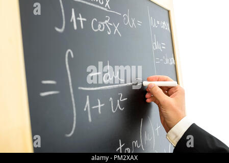 Primo piano dello scienziato calcolo equazione matematica complessa sulla lavagna nera. Foto Stock