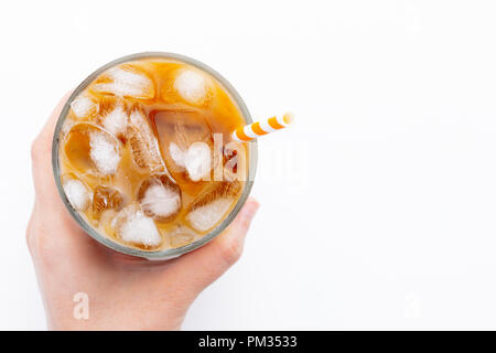 Latte macchiato di ghiaccio top view close up su sfondo bianco e i tracciati di ritaglio. Con copia spazio. Una donna di mano trattiene un bicchiere di caffè freddo. Foto Stock