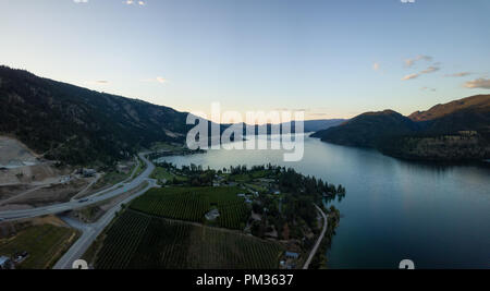 Antenna vista panoramica di case nei pressi di un lago durante una vibrante estate tramonto. Situato nei pressi di Kelowna e Vernon, BC, Canada. Foto Stock