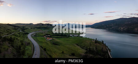 Antenna vista panoramica di una autostrada vicino Kalamalka Lago durante una vibrante estate tramonto. Situato tra Kelowna e Vernon, BC, Canada. Foto Stock