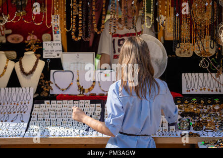 RIGA, Lettonia - 31 luglio 2018: una donna nel chiosco di souvenir scegliere gioielli in ambra. Foto Stock