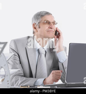 Imprenditore esperto con telefono cellulare seduto alla sua scrivania Foto Stock